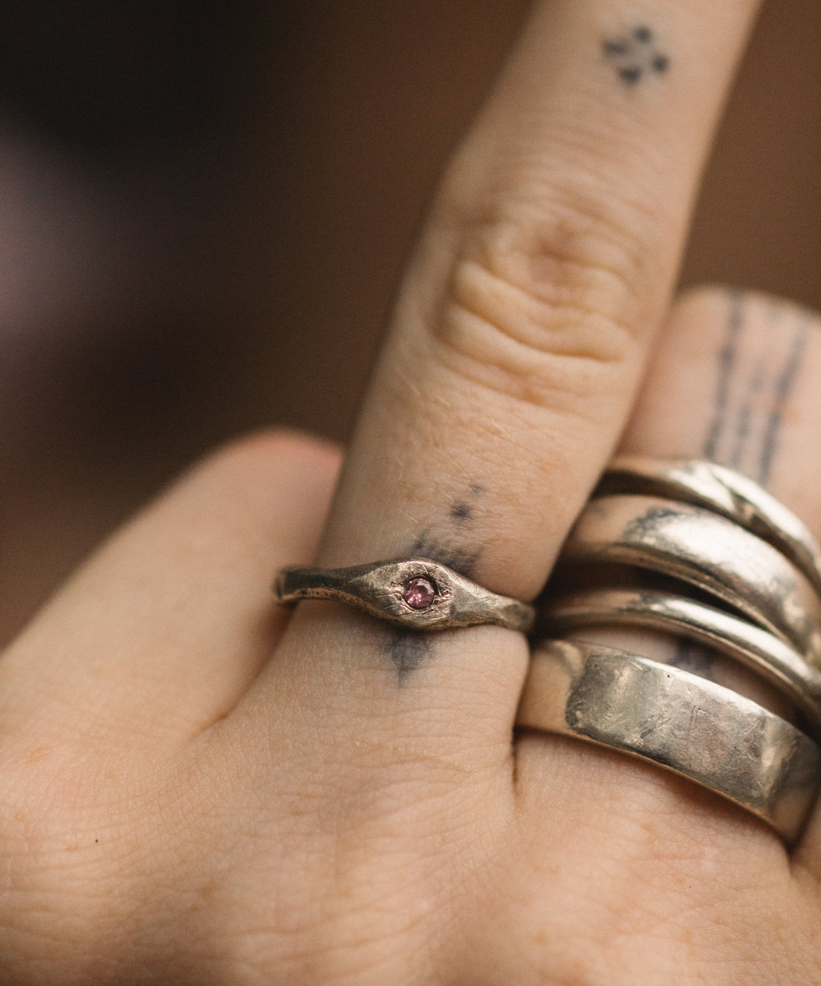 Close-up of a hand wearing two silver rings with a small gemstone on a blurred background