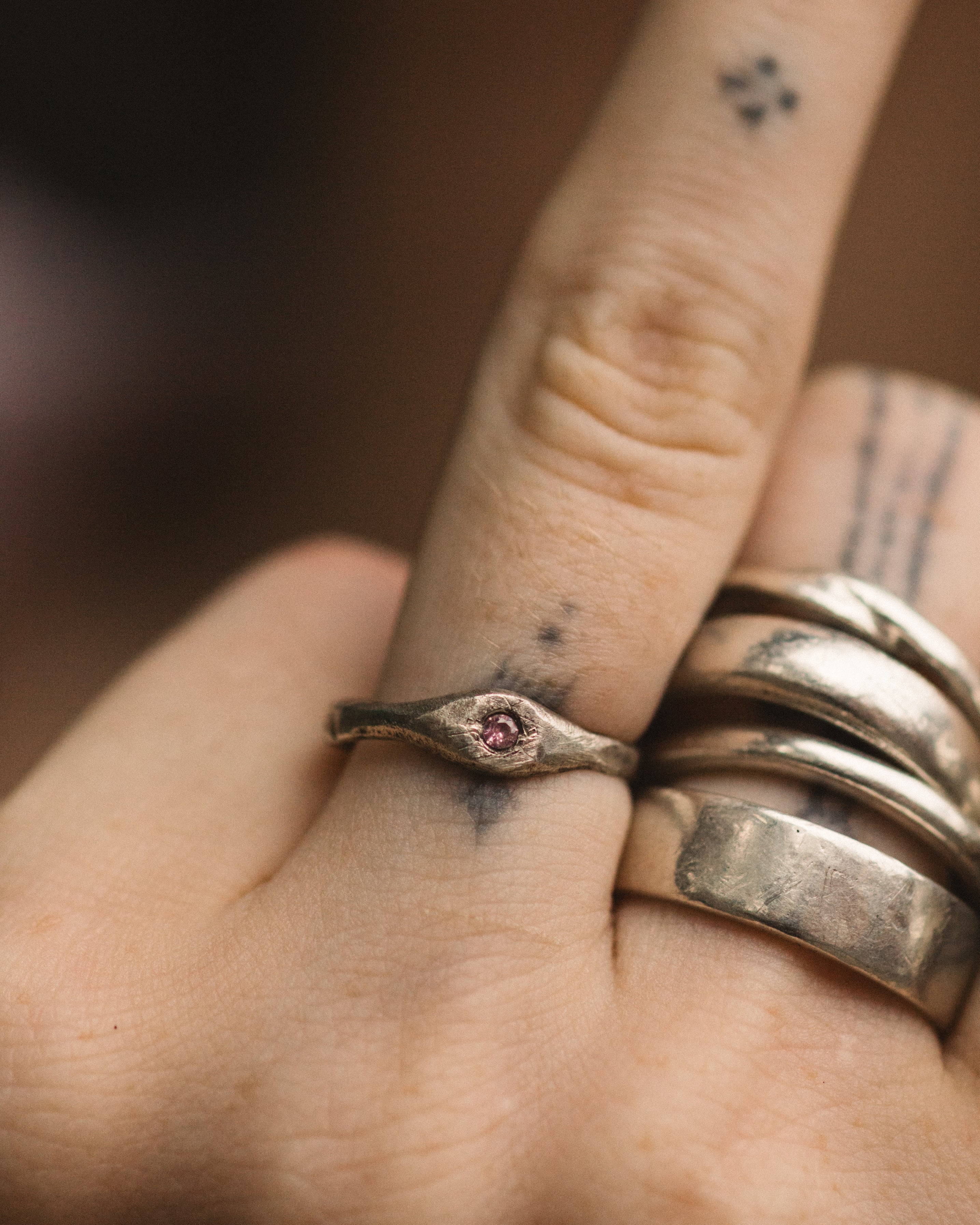 Close-up of a hand wearing two silver rings with a small gemstone on a blurred background