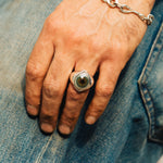 Hand wearing a ring and chain bracelet on denim fabric