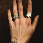 Hand wearing two rings with a dark background