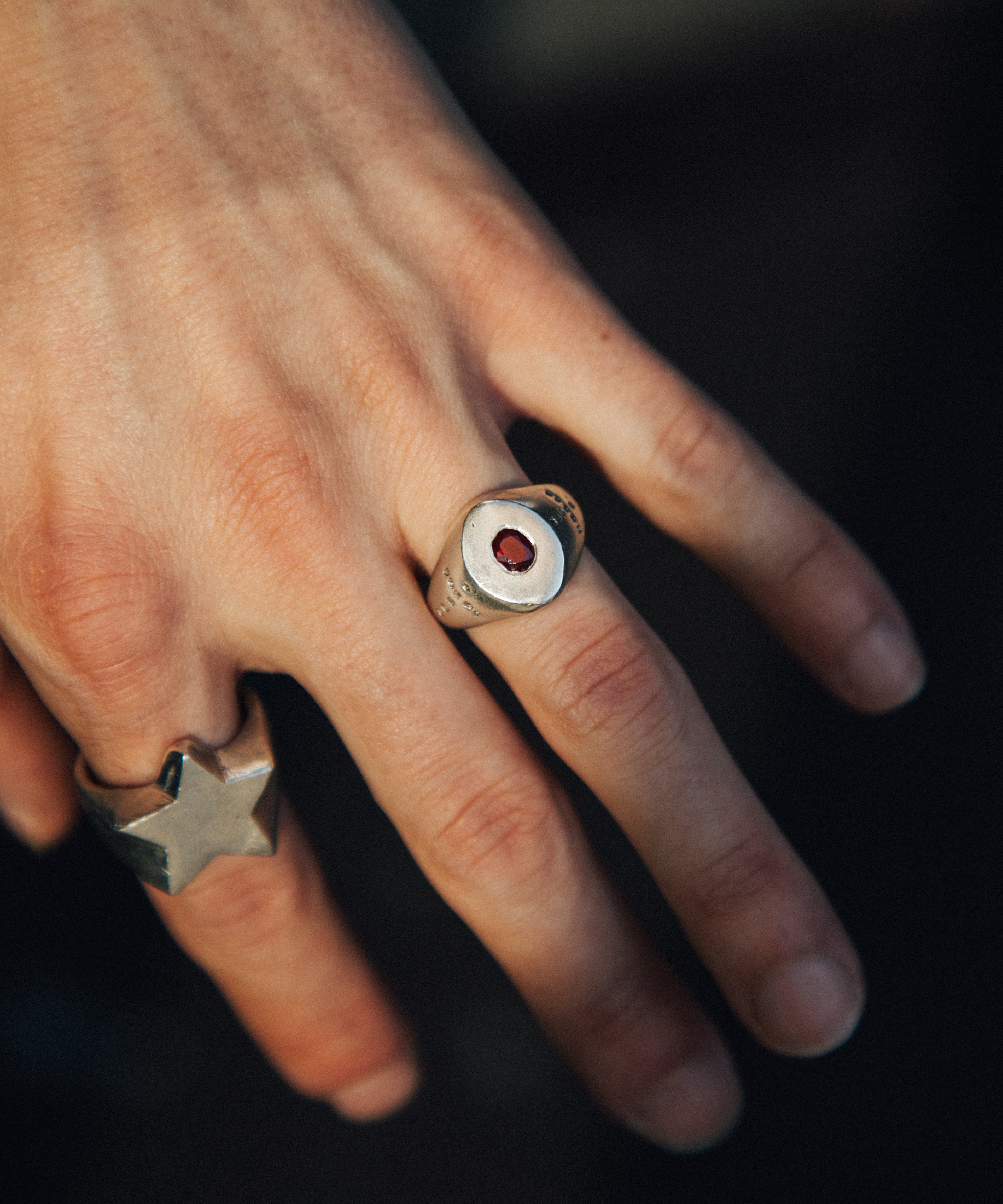 Close-up of a hand wearing two rings with a dark background