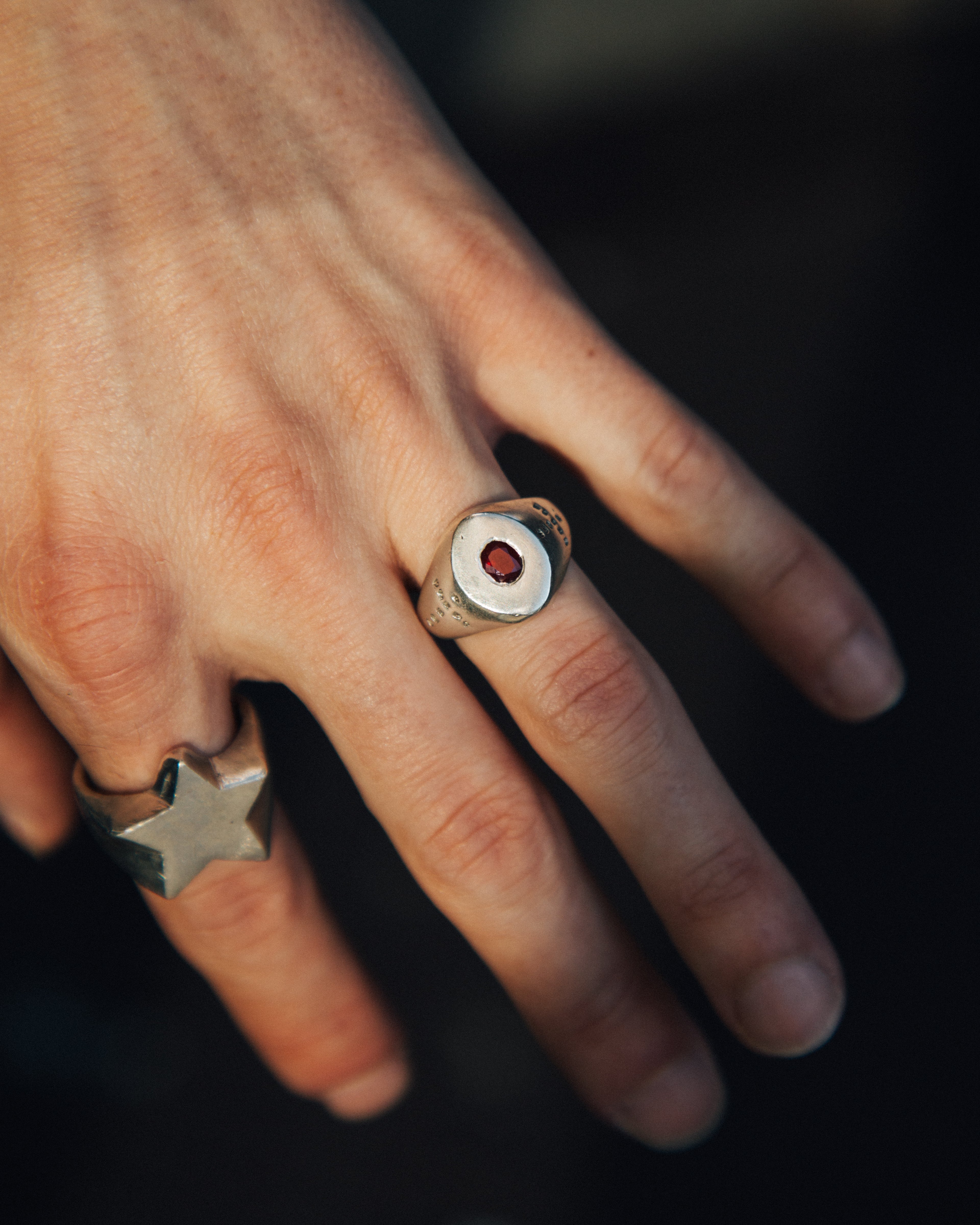 Close-up of a hand wearing two rings with a dark background