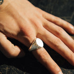 Close-up of a hand wearing a silver ring on a dark surface
