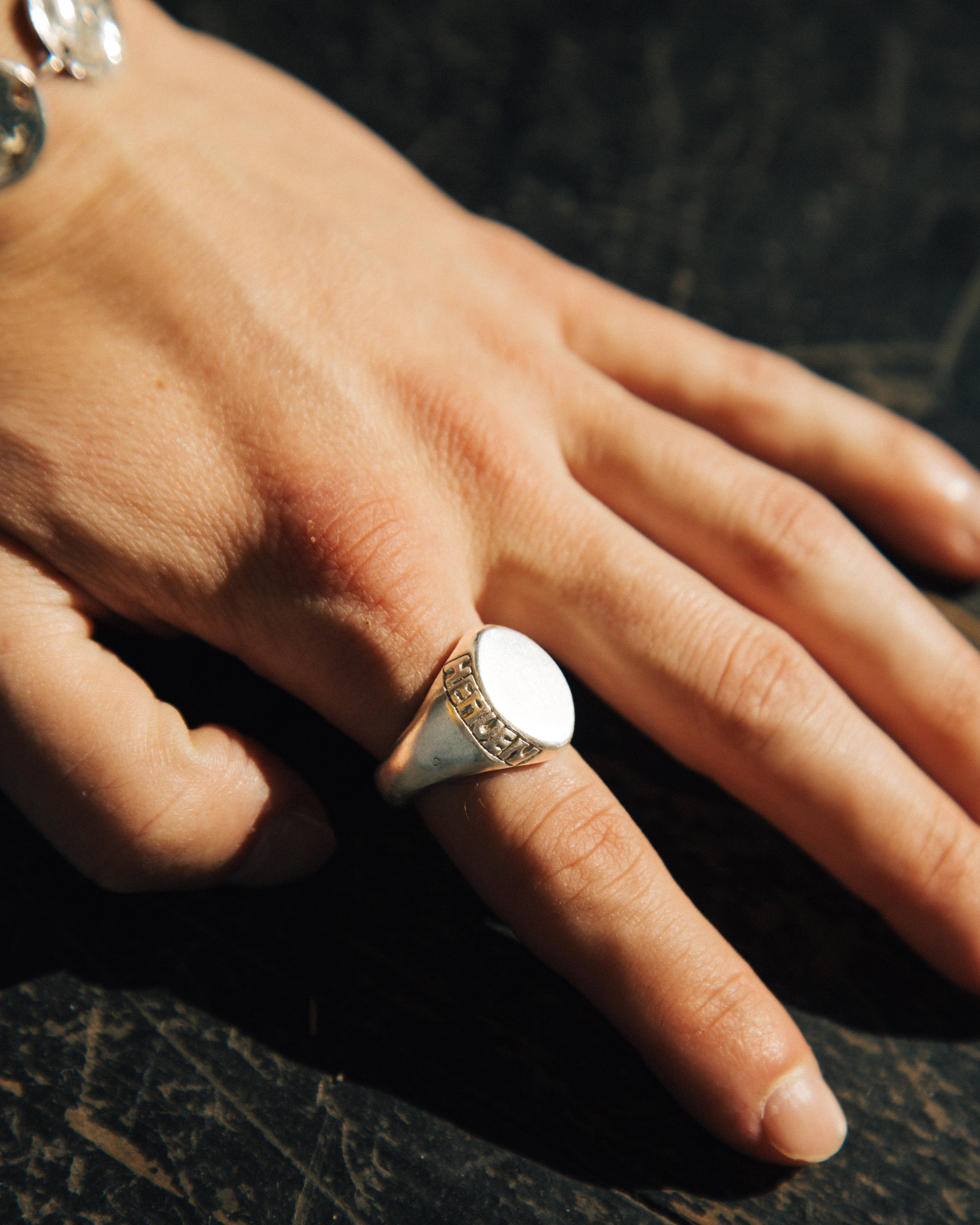 Close-up of a hand wearing a silver ring on a dark surface