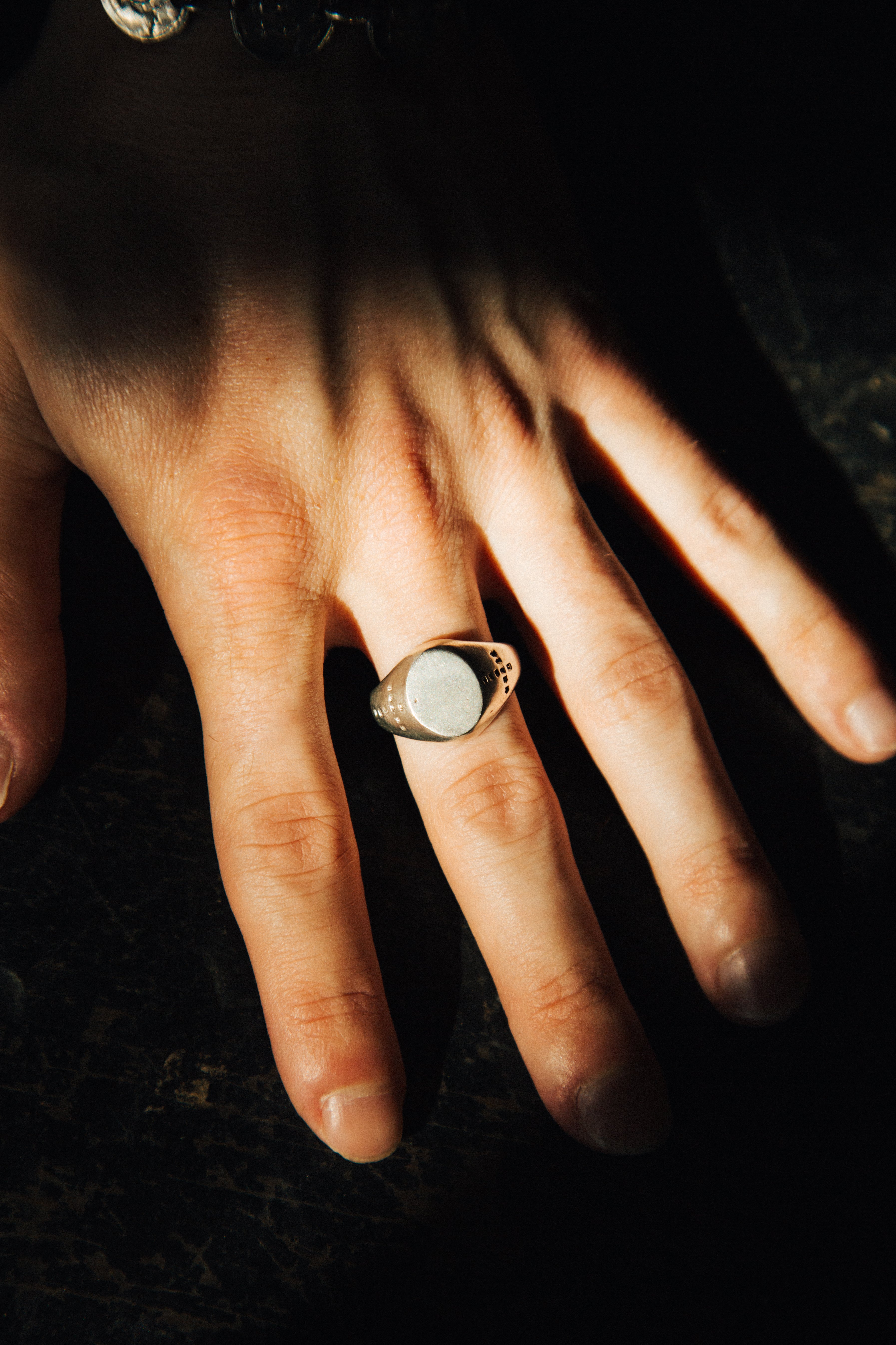 Hand wearing a ring on a dark background