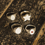 Four rings with different designs on a textured surface