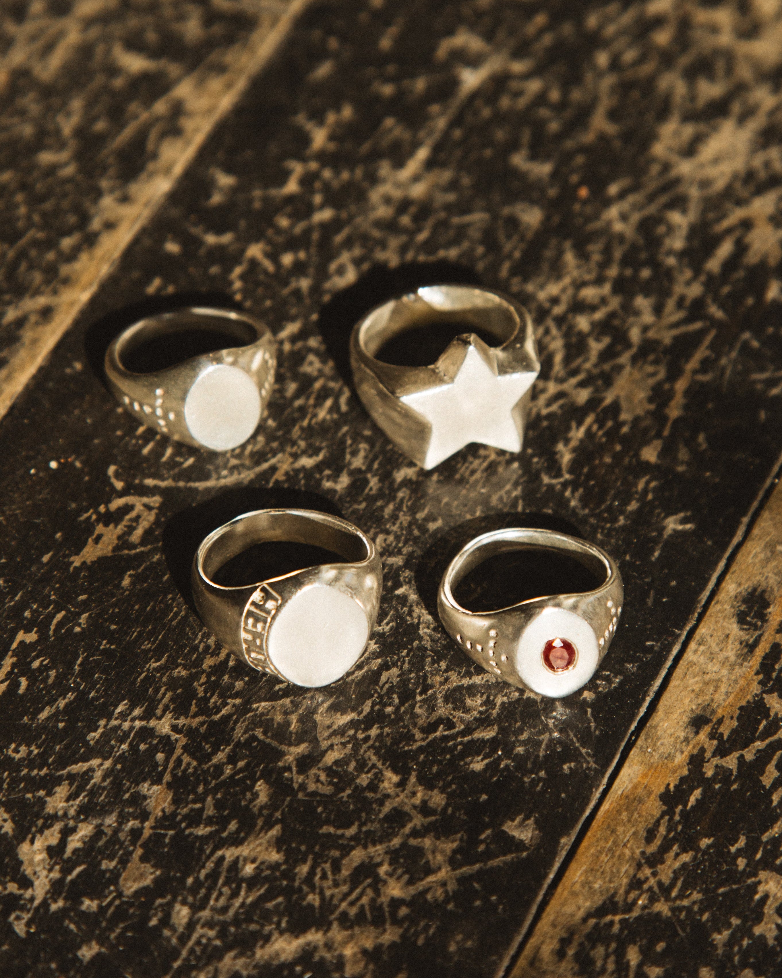 Four rings with different designs on a textured surface