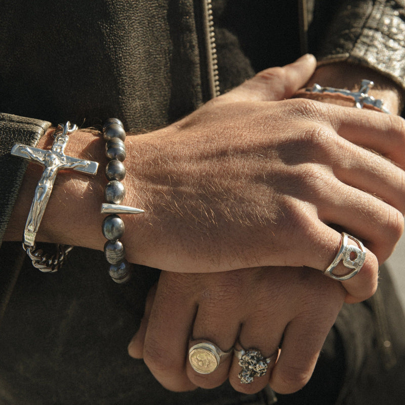 Close-up of a person's hands with multiple silver rings and bracelets on a dark background