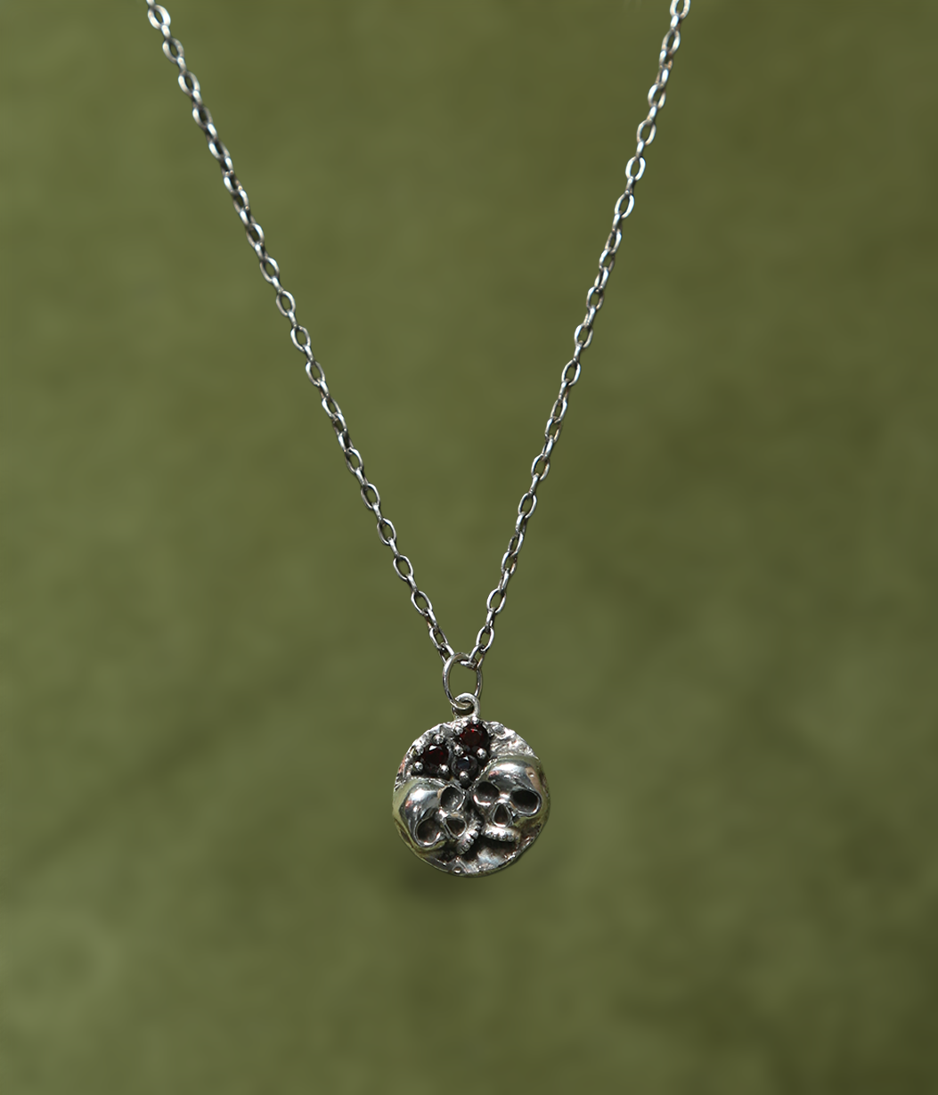 Silver necklace with a round pendant on a green background