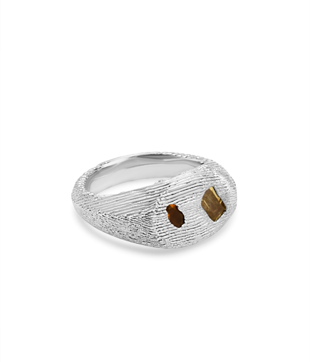 Silver ring with textured surface and embedded stones on a white background