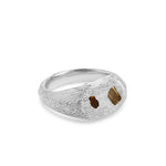 Silver ring with textured surface and embedded stones on a white background