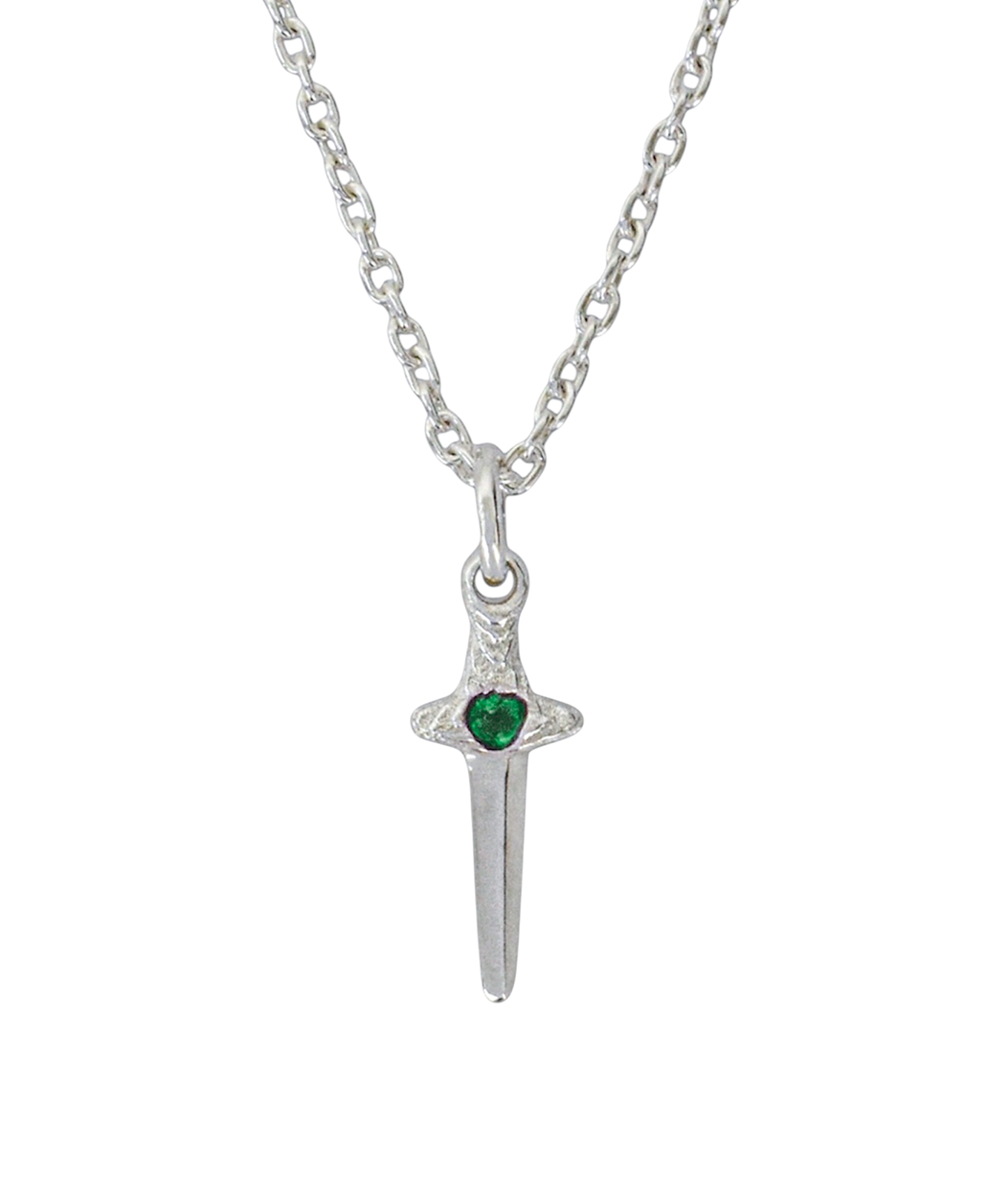 A silver pendant necklace featuring a miniature dagger or sword charm with a small, heart-shaped green gemstone at the center of the crossguard, suspended from a silver link chain against a plain white background.