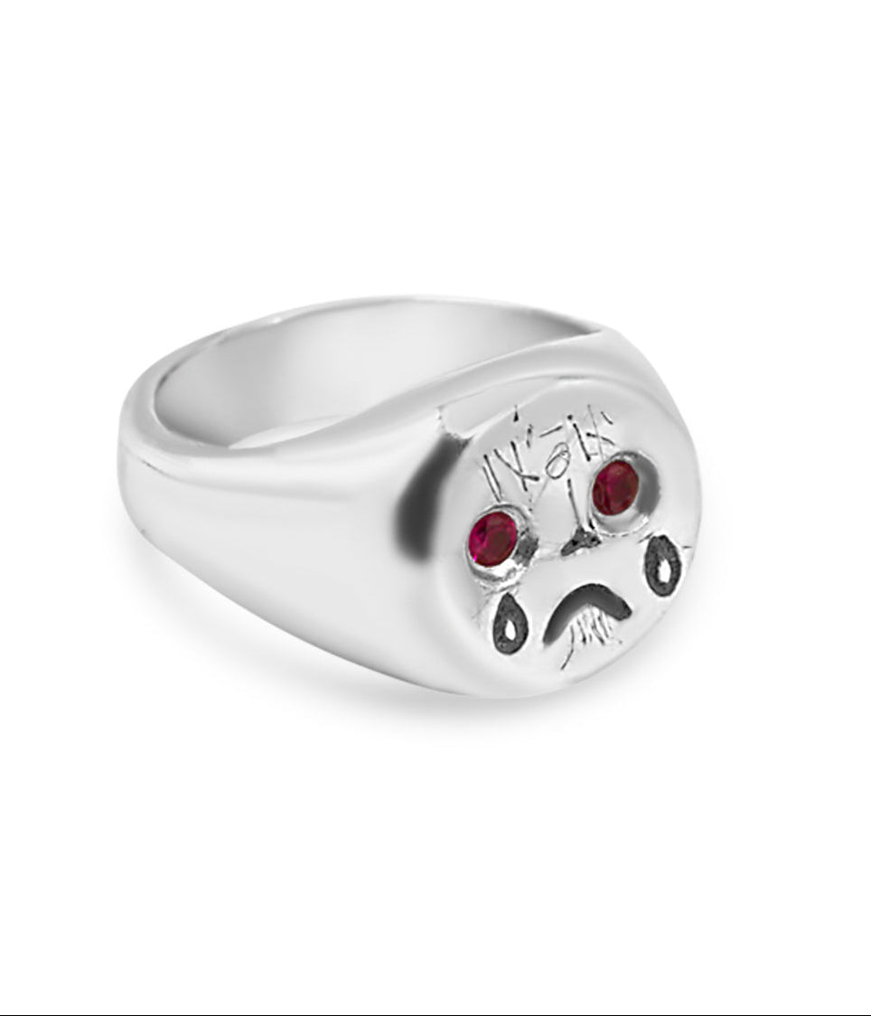Silver ring with paw print design and red stones on a white background