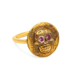Gold skull ring with red gemstones on a white background