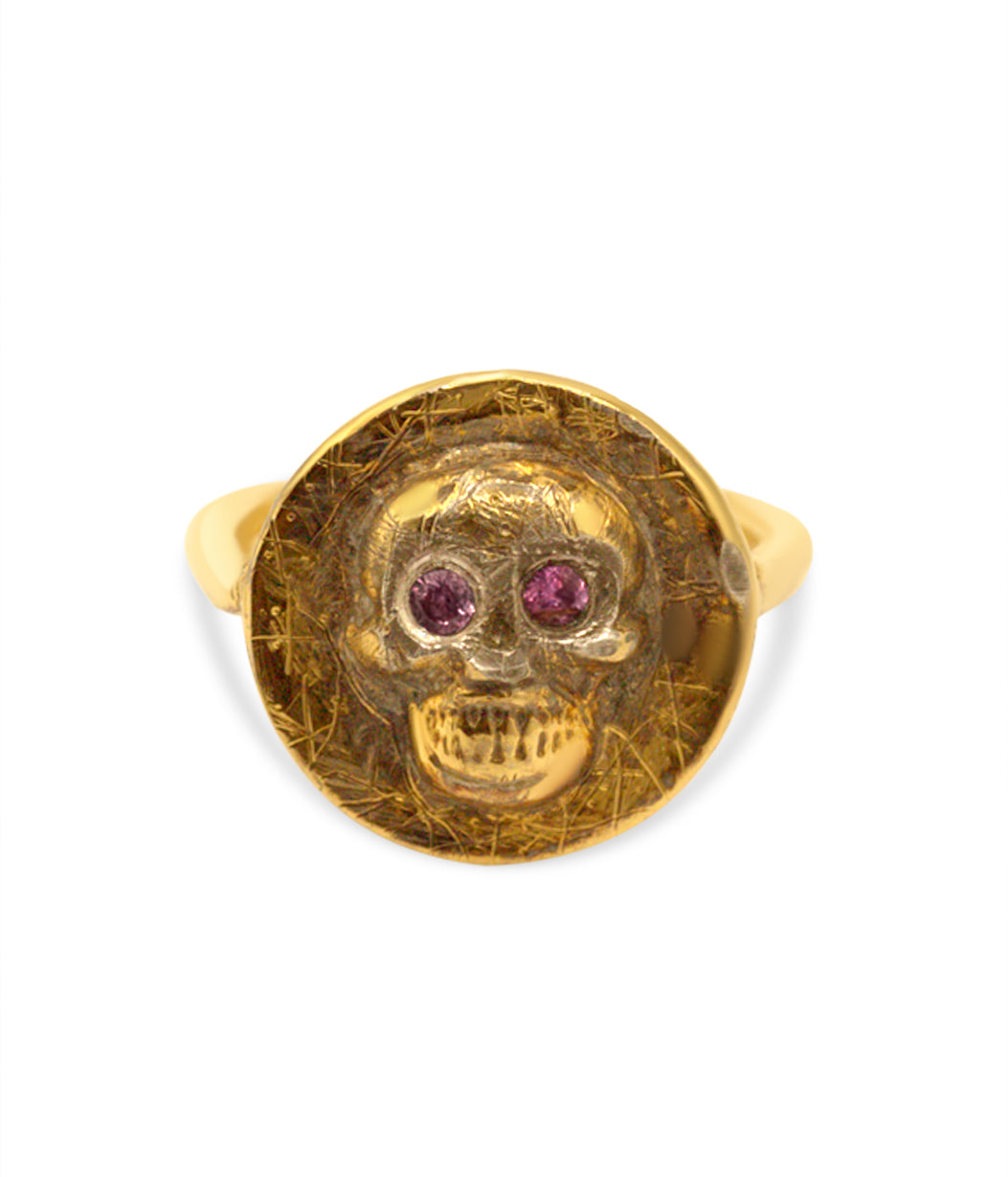 Gold skull ring with red gemstones on a white background