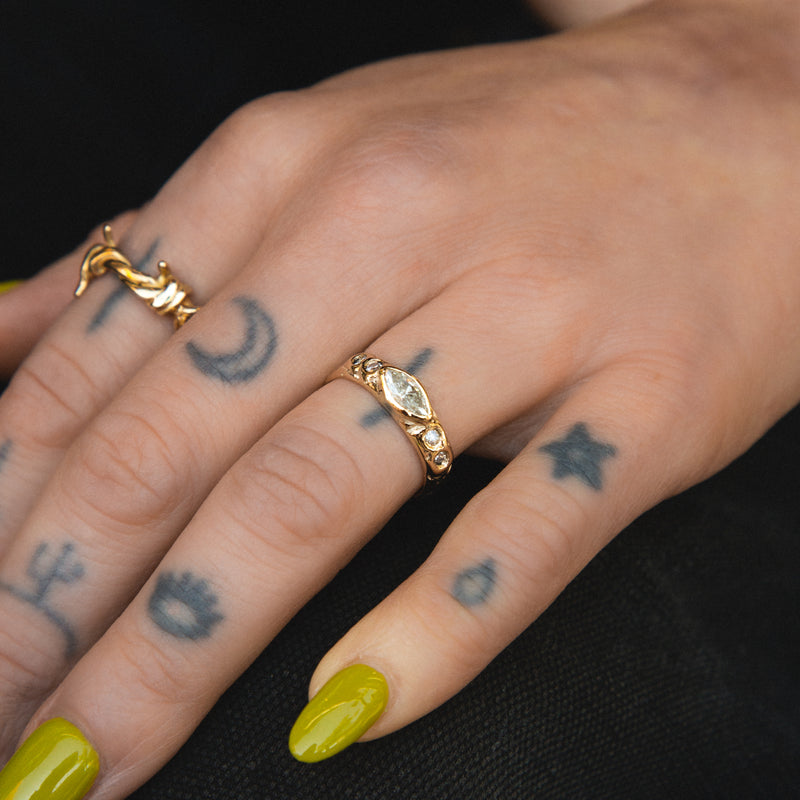 Close-up of a hand with gold rings and tattoos on a black background