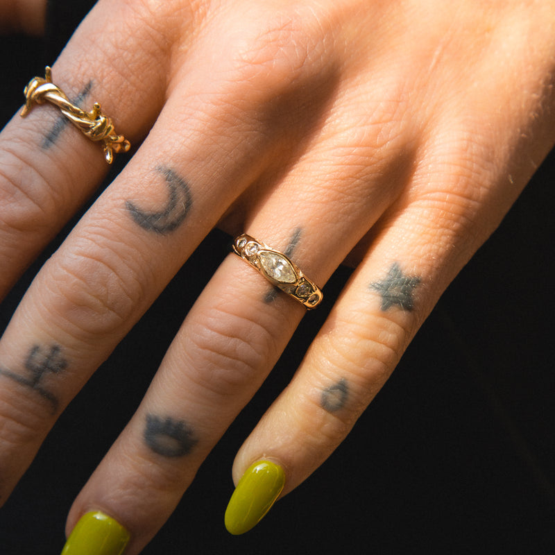 Close-up of a hand with gold rings and tattoos on a black background