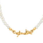 Necklace with white beads and a gold barbwire clasp on a white background