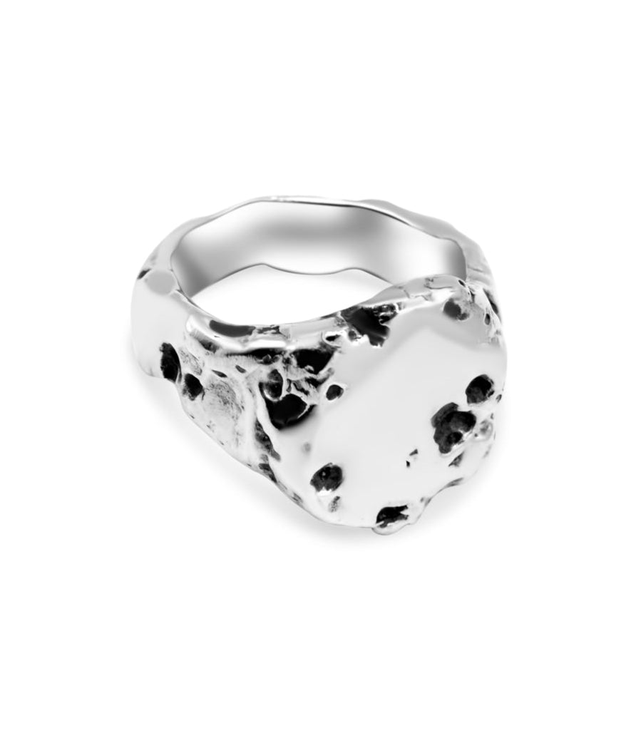 Silver ring with black speckles on a white background