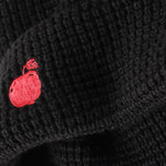 Black textured fabric with a red embroidered design on a dark background