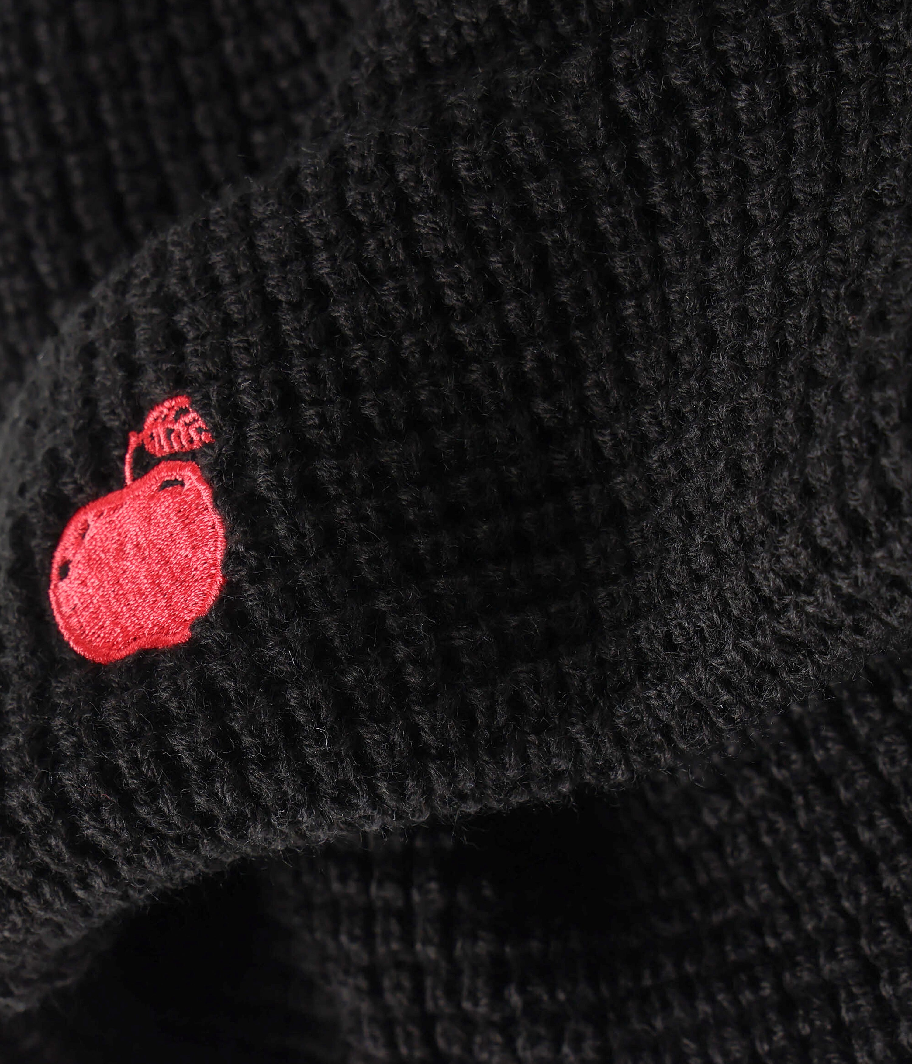 Black textured fabric with a red embroidered design on a dark background