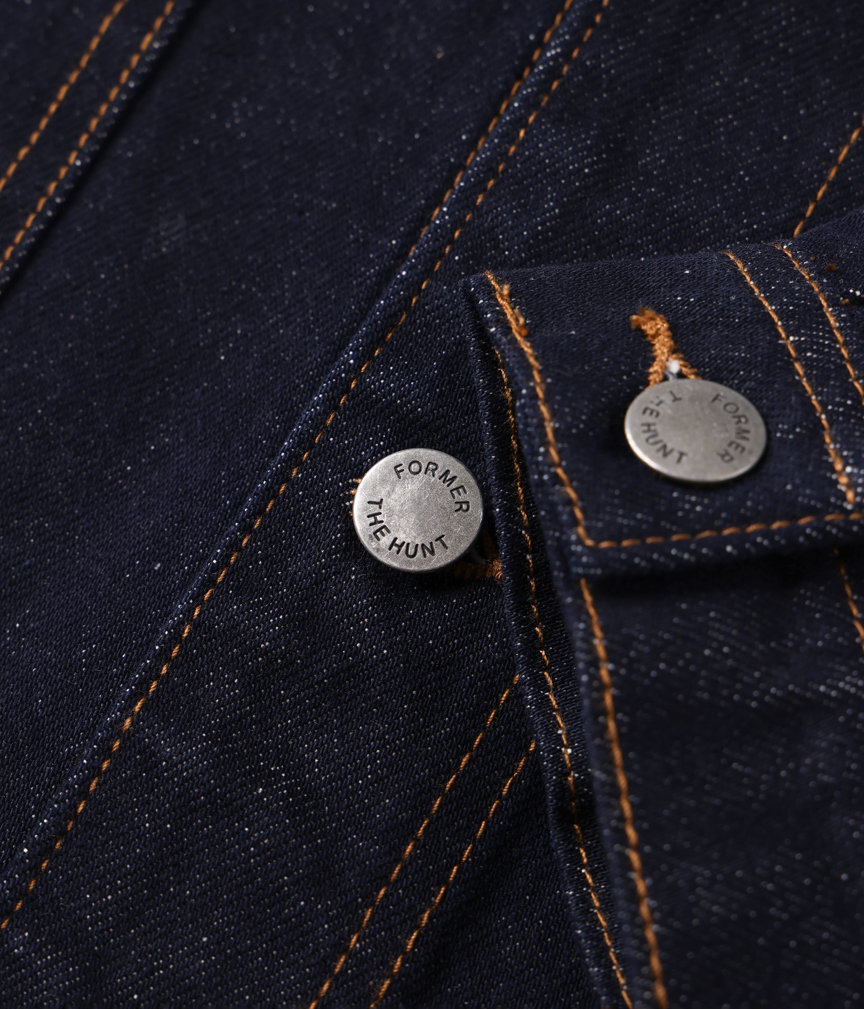 Close-up of a dark denim jacket with 'Former' branding on buttons.