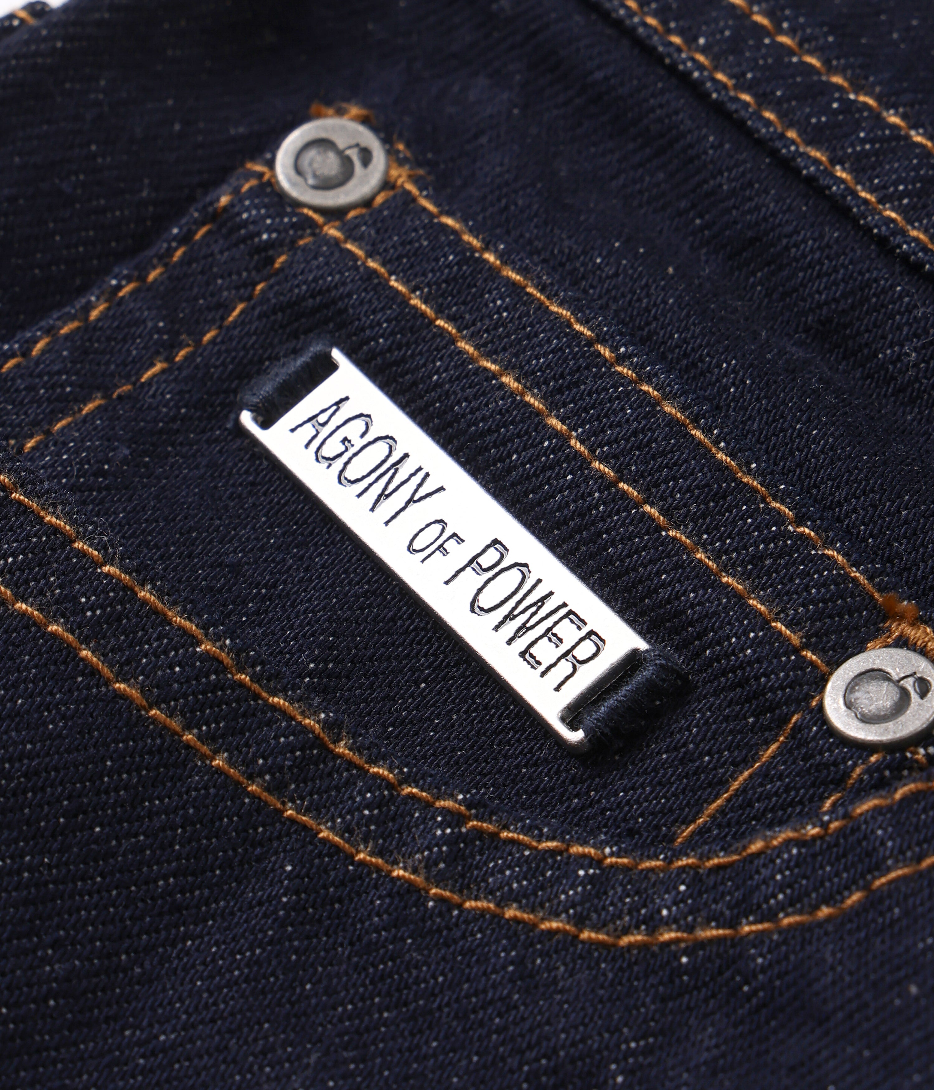 Close-up of a denim fabric with 'Agony of Power' label.