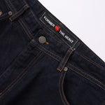 Close-up of dark blue denim jeans with a brand label on a white background