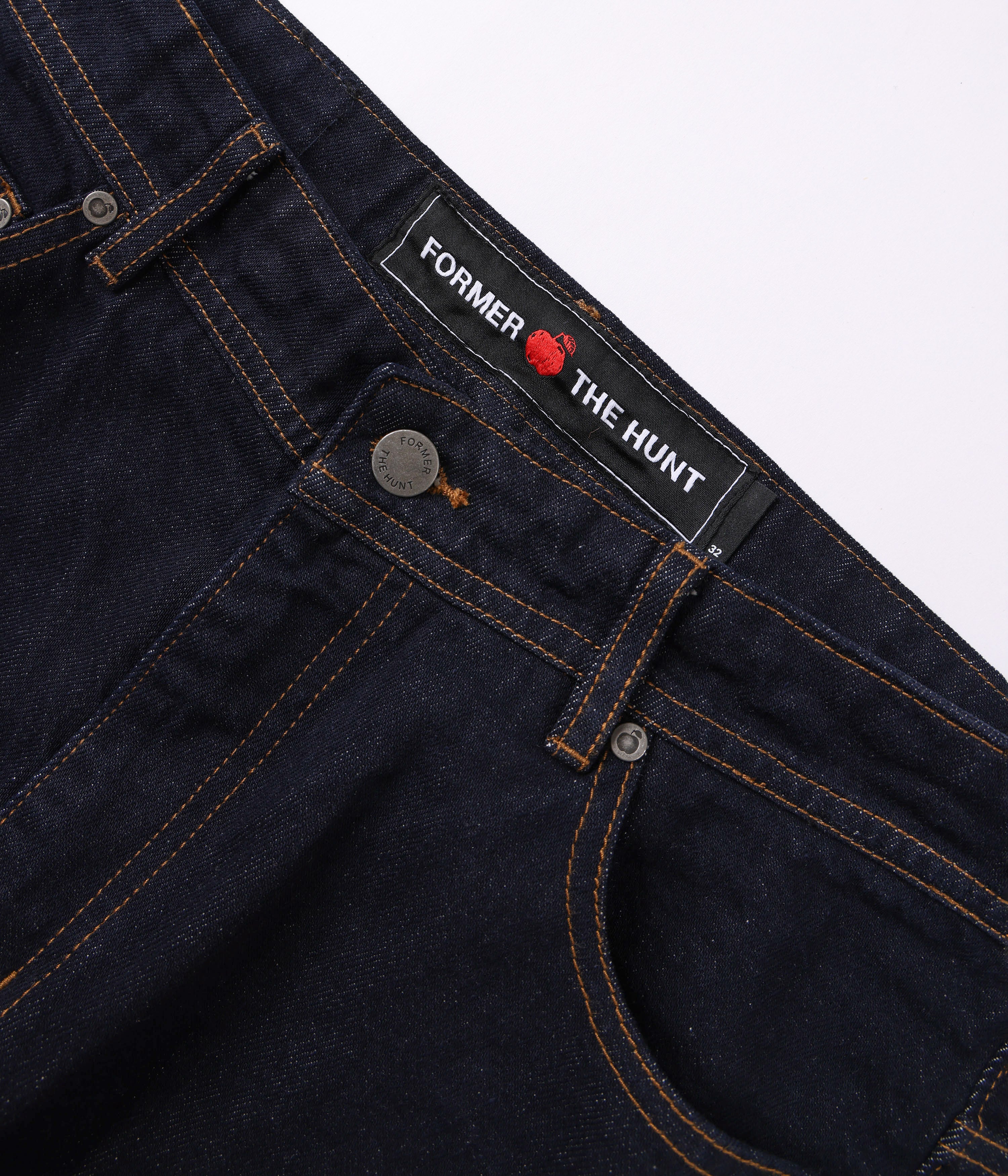 Close-up of dark blue denim jeans with a brand label on a white background