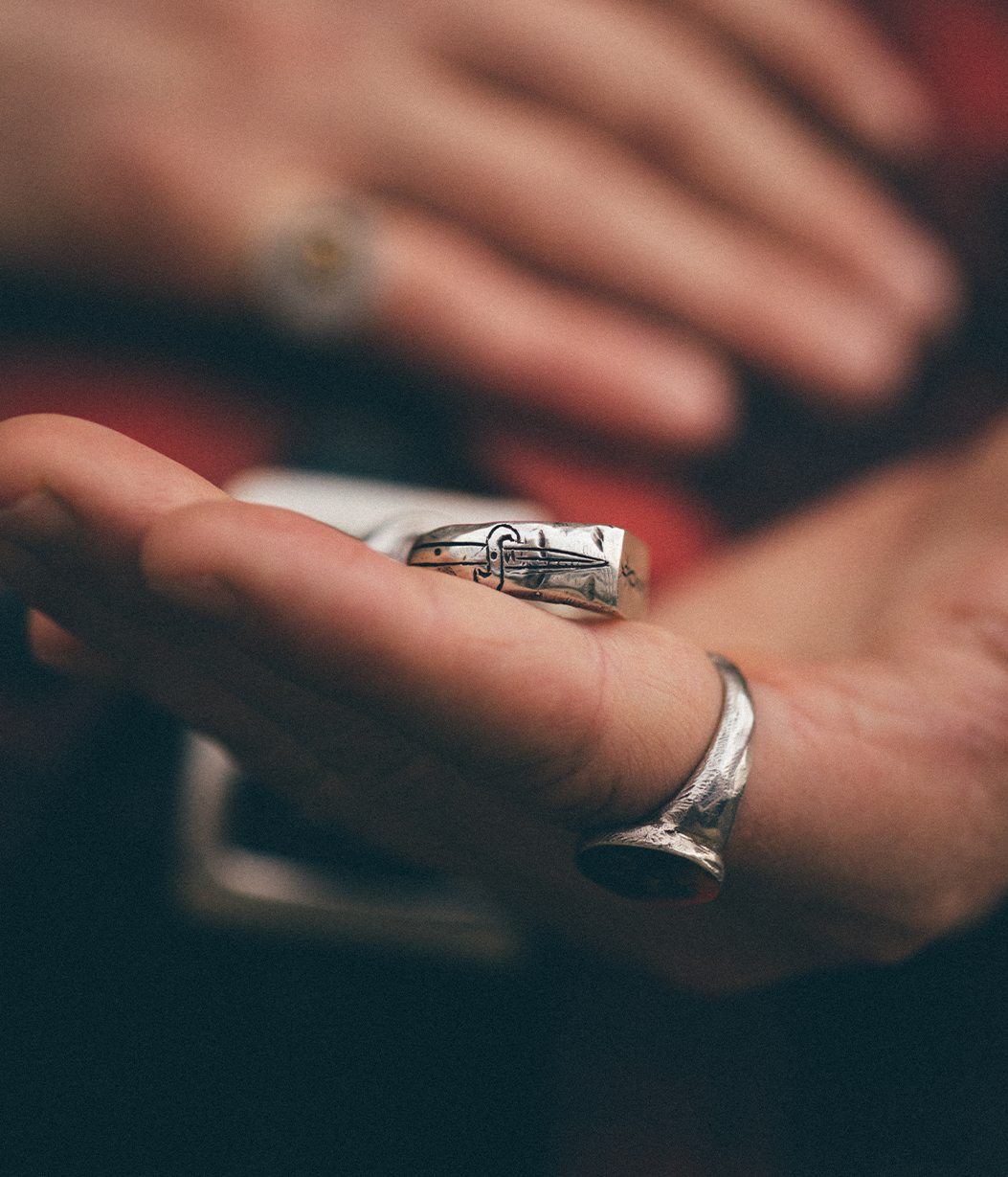 side of a silver ring with a dagger engraving