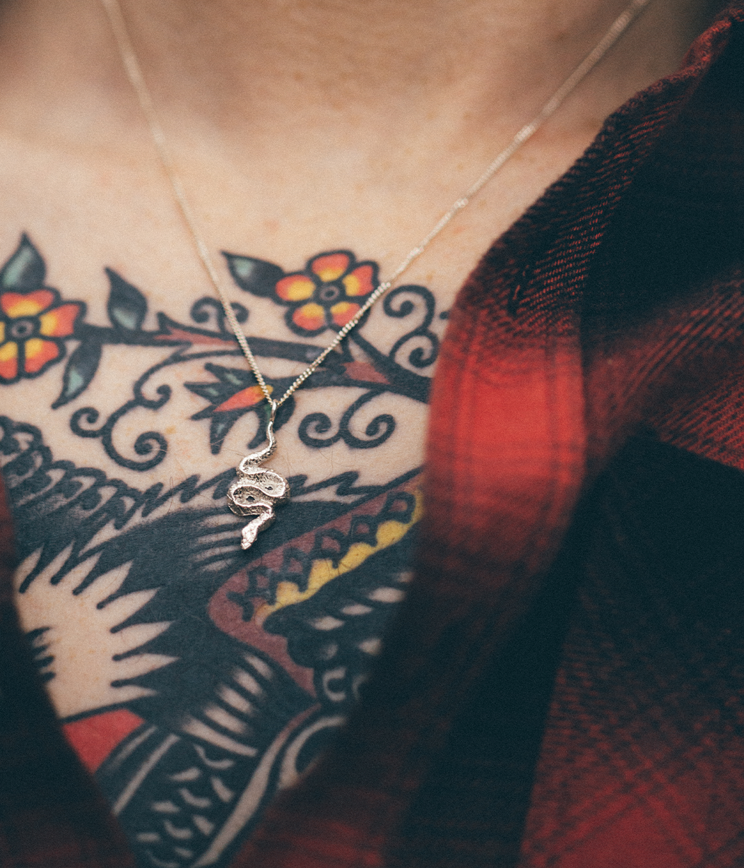 snake pendant necklace on tattooed chest