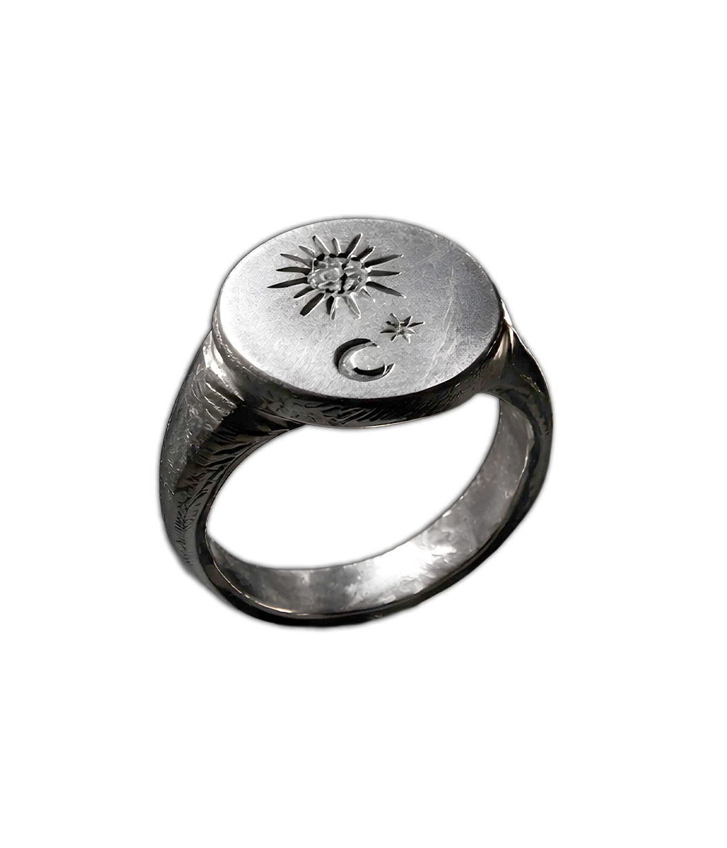 A silver signet ring featuring engraved crescent moon and star symbols on the top, shown against a plain white background.