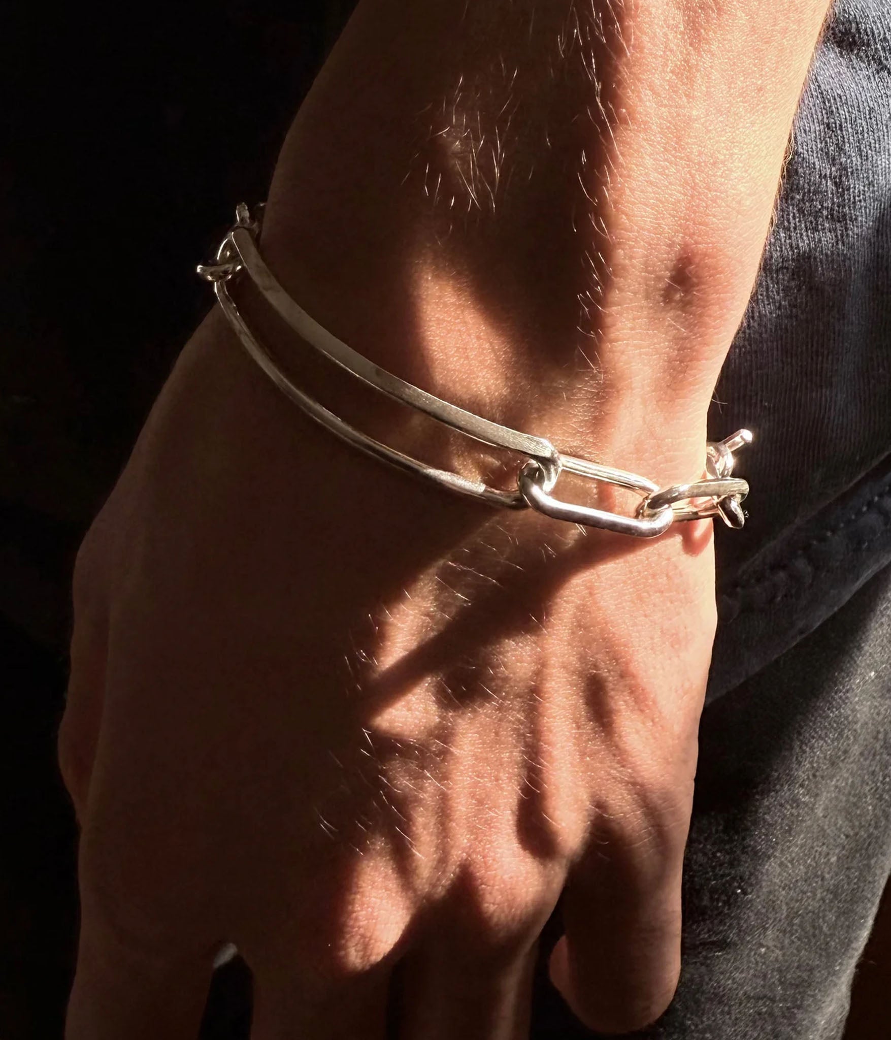 Knife edged chain bracelet with a toggle clasp on male models hand 