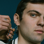 Man getting an earring put in his ear with a dark background