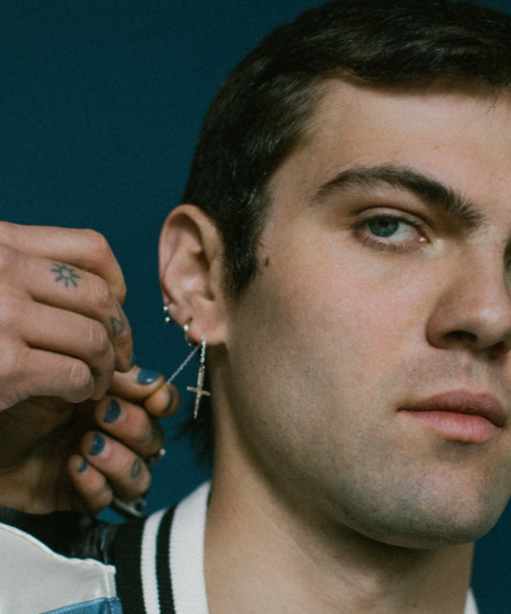 Man getting an earring put in his ear with a dark background