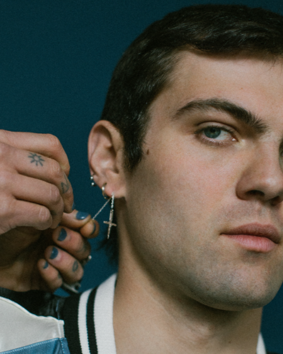 Man getting an earring put in his ear with a dark background