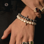 Close-up of a hand wearing multiple rings and bracelets on a dark background