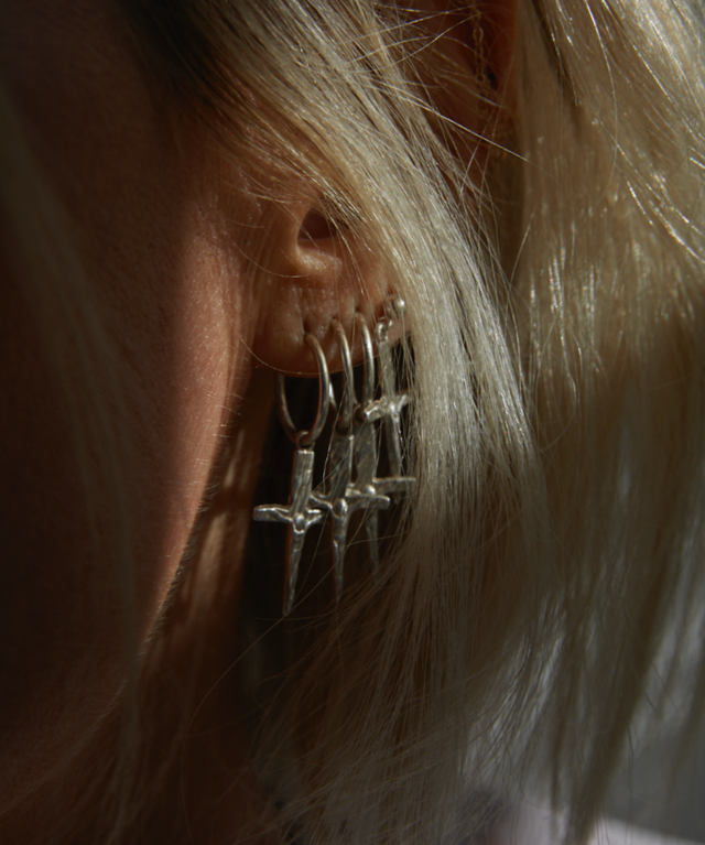 Close-up of an ear wearing a silver earring with a blurred background