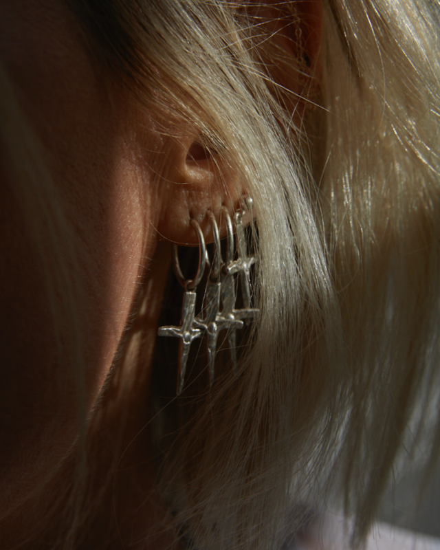 Close-up of an ear wearing a silver earring with a blurred background