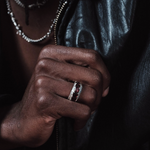 Close-up of a hand wearing a ring with a dark background