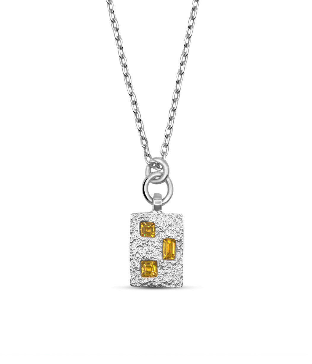 Silver pendant with yellow gemstones on a white background