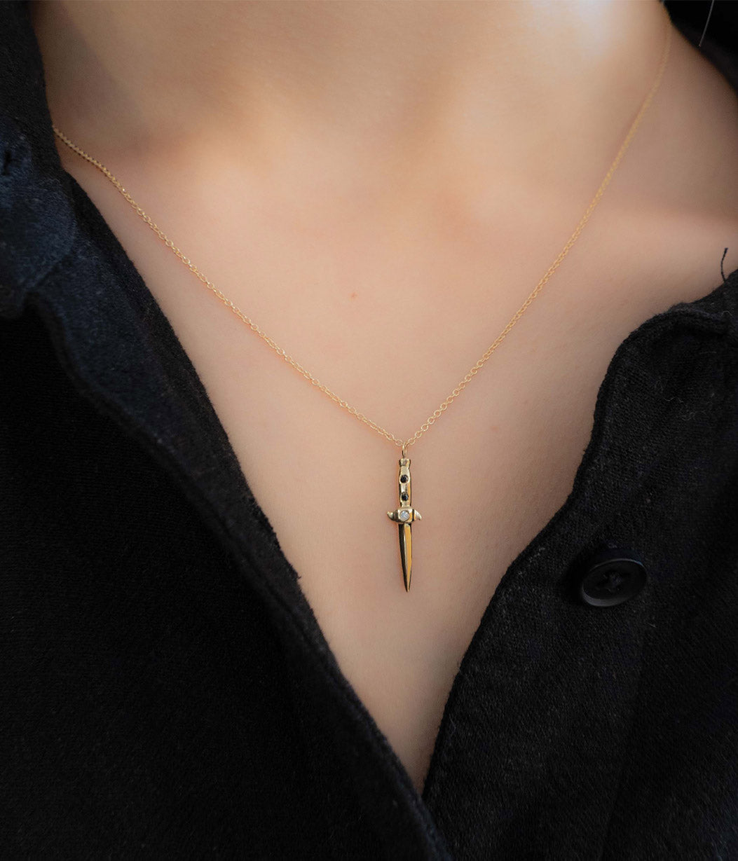 Gold necklace with a unique pendant on a mannequin wearing a black top.
