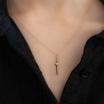 Gold necklace with a unique pendant on a mannequin wearing a black top.