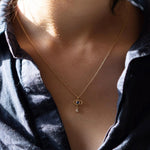 Necklace with a pendant worn by a person against a dark shirt.