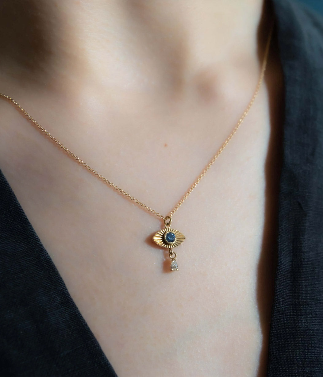 Gold necklace with a pendant worn by a person against a dark background