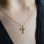 Gold necklace with a pendant worn by a person against a dark background