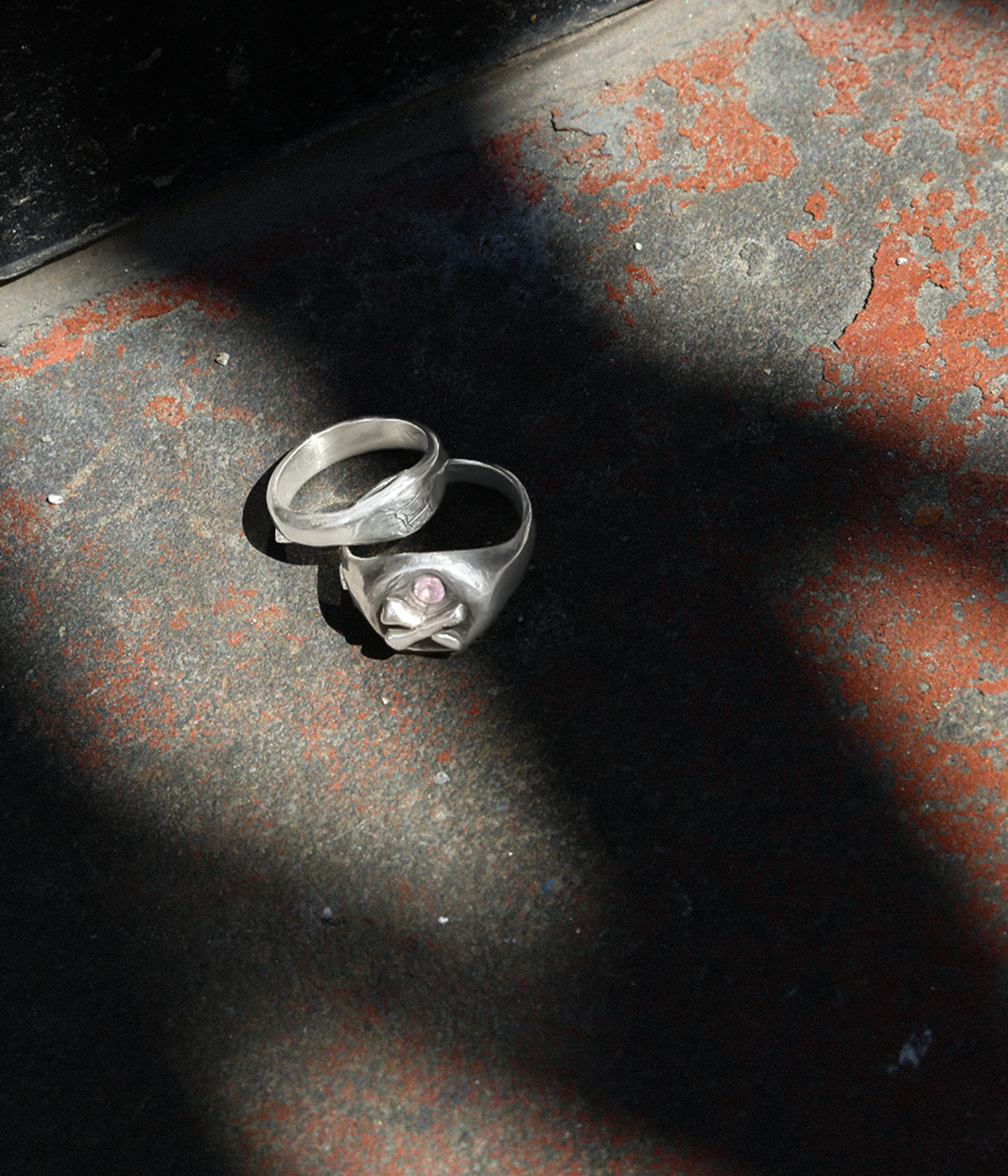 Silver ring with a pink stone on a textured surface