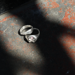 Silver ring with a pink stone on a textured surface