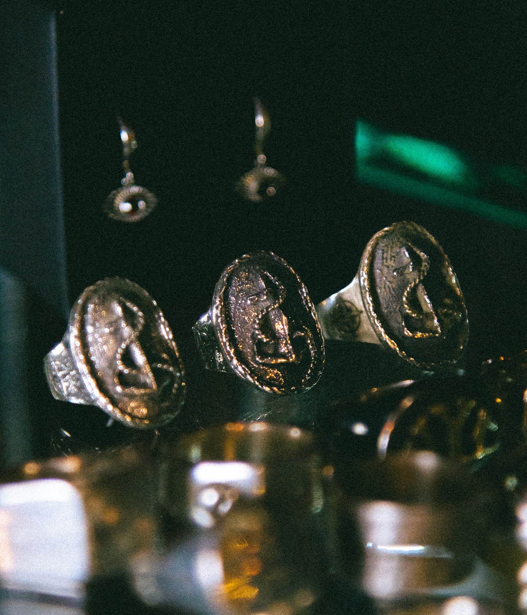 Close-up of gold rings with engraved faces on a reflective surface.