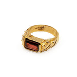 Gold ring with a red gemstone on a white background
